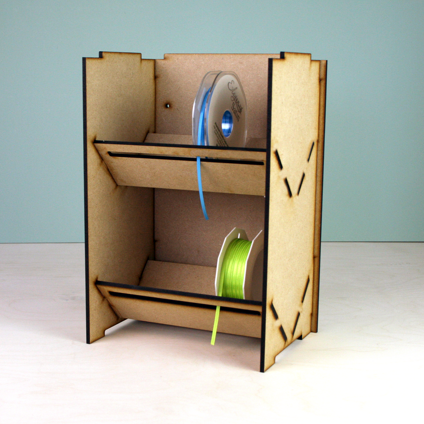 Laser cut MDF ribbon holder in front of green background