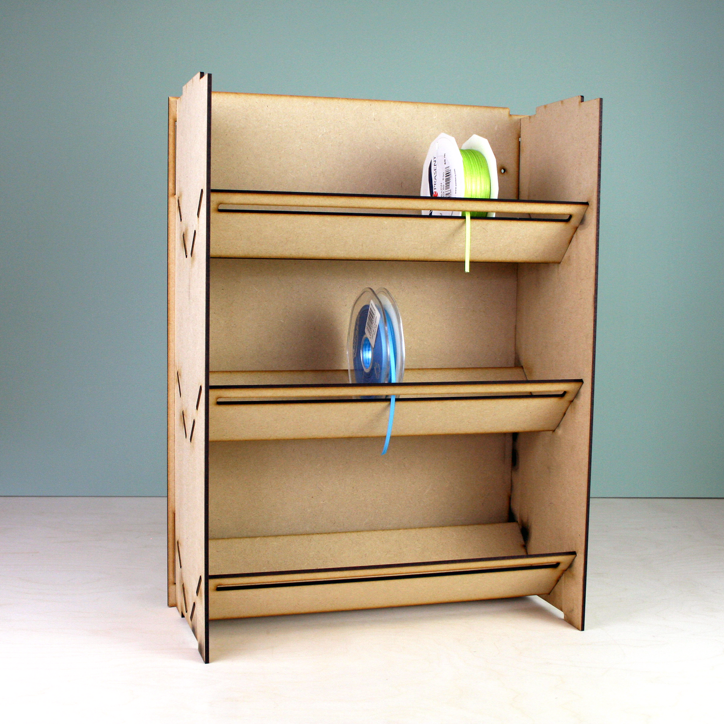 Laser cut MDF ribbon holder in front of green background