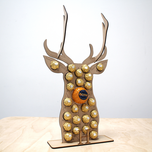 Reindeer shaped MDF advent calendar filled with chocolate on table in front of white background