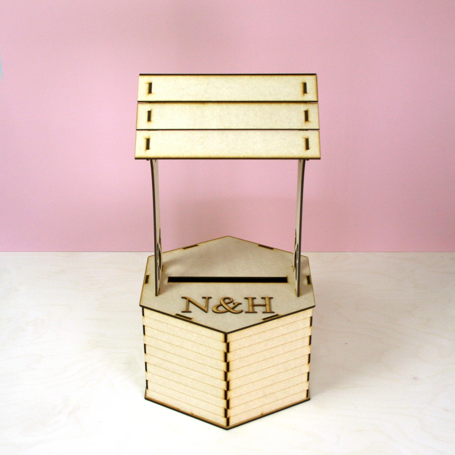 MDF wishing well shaped postbox for cards in front of pink background